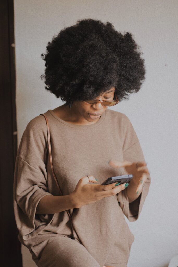 Woman scrolling through different natural hair tips and advice online