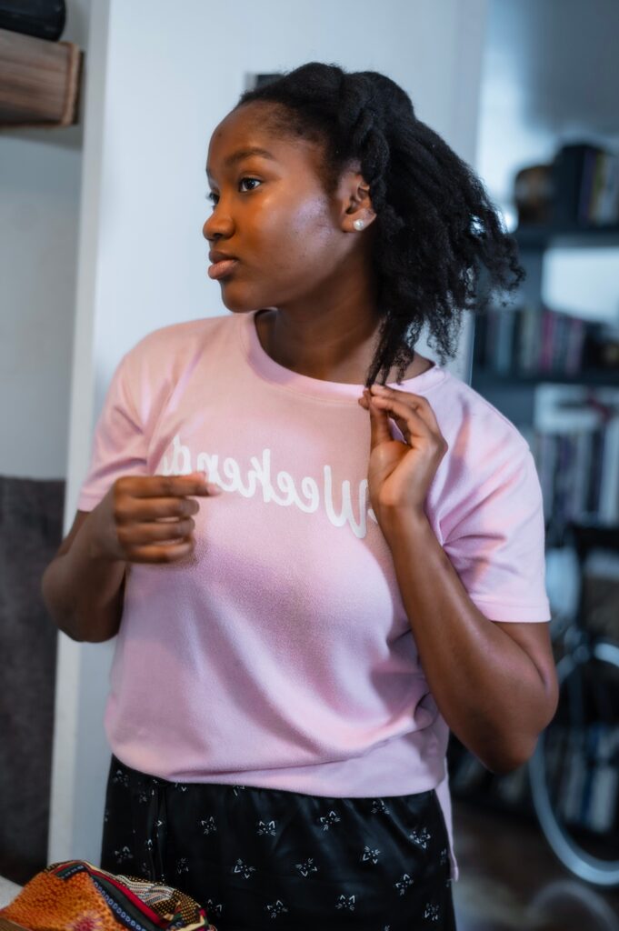 Black woman examining a section of healthy 4C hair during a monthly hair check.