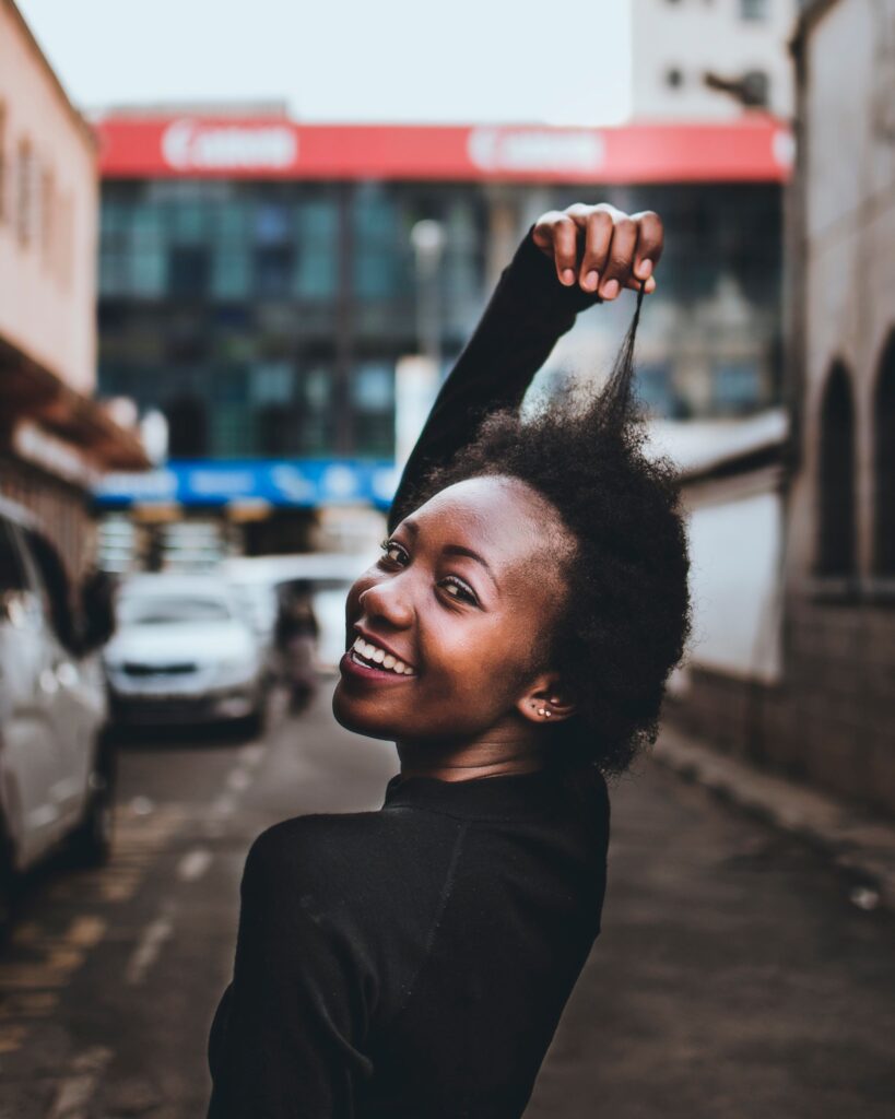 Lady smiling while stretching her healthy natural hair to check progress.