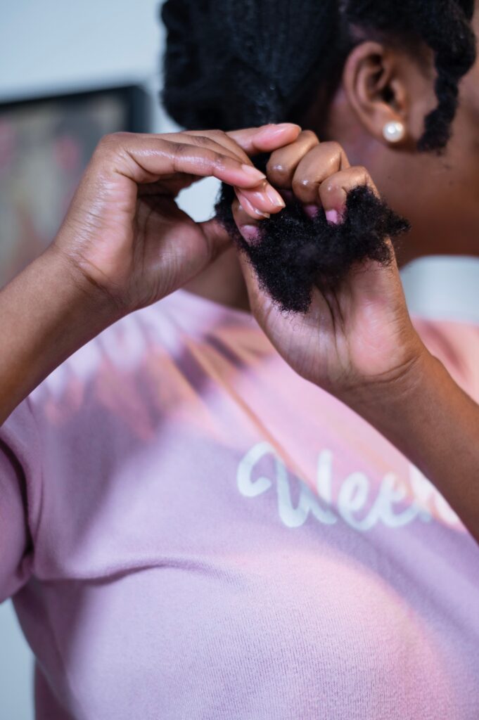 Woman applying moisturizer to natural 4C hair