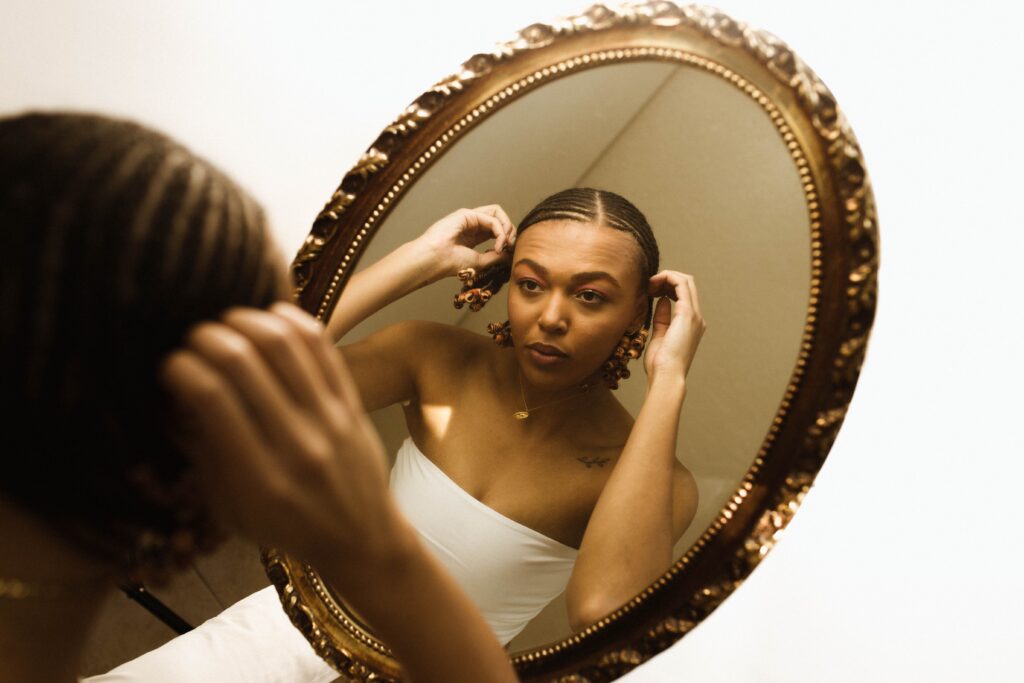 Woman looking at her protective hairstyle in a mirror while checking its condition.