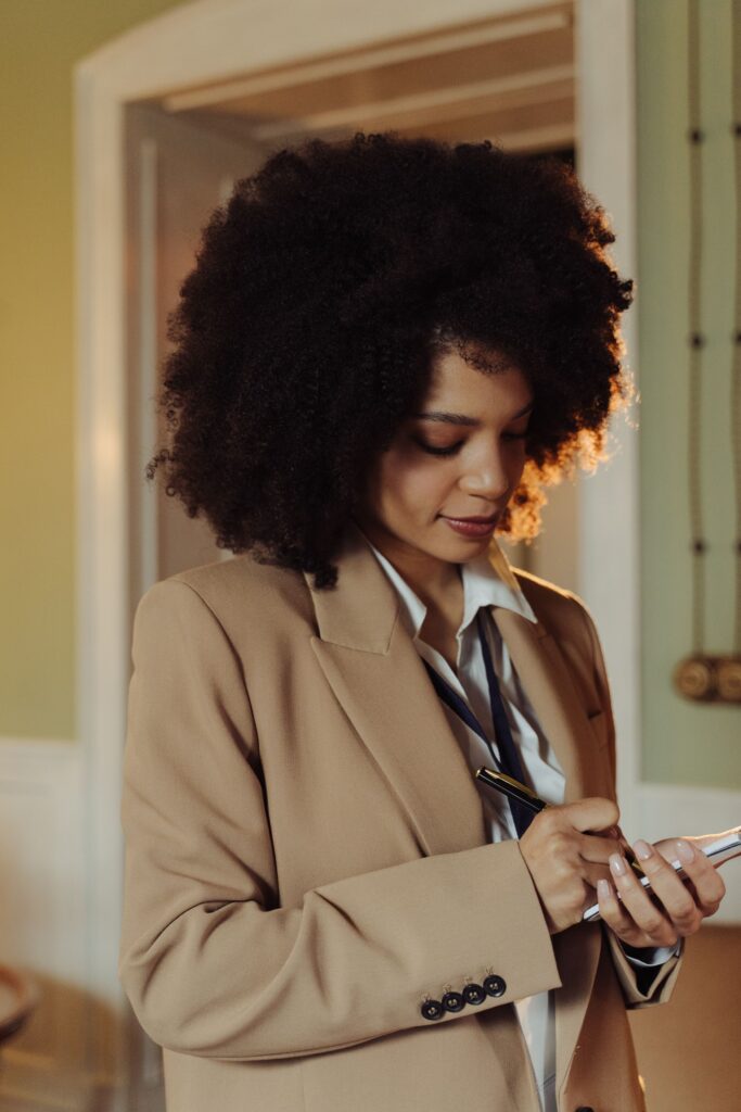 Woman planning her weekly 4C hair routine with a notebook and calendar,