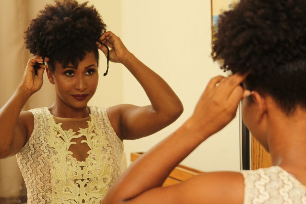 A woman confidently styling her natural 4C hair at home