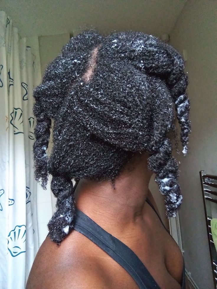 Black woman applying conditioner to sectioned natural 4C hair.