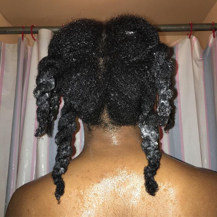 Black woman sectioning natural 4C hair while applying a deep conditioner correctly.