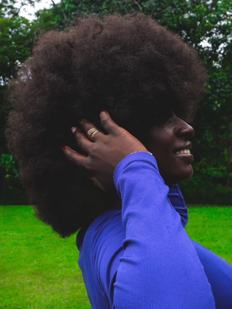 Black woman running her hand through healthy, moisturized 4C hair with visible definition and volume.
