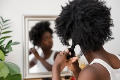 Woman examining healthy natural 4C hair to prevent breakage.