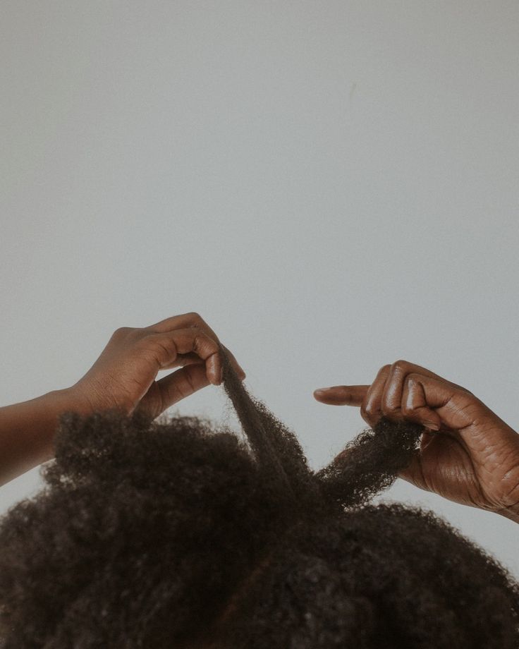 Black woman gently finger-detangling her 4C hair before wash day.