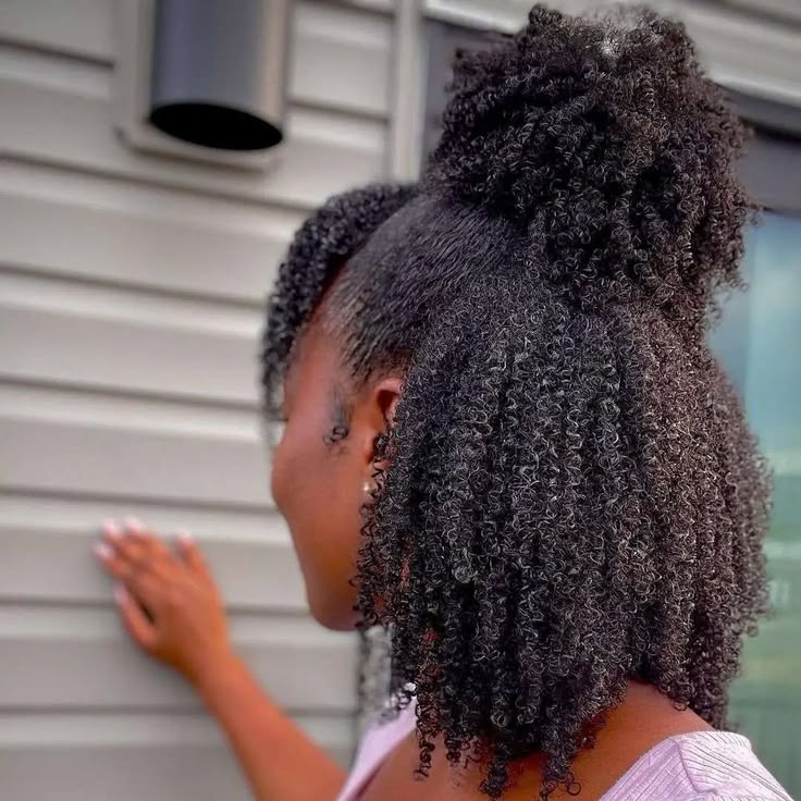 Black woman with moisturized natural 4C hair after applying leave-in conditioner.
