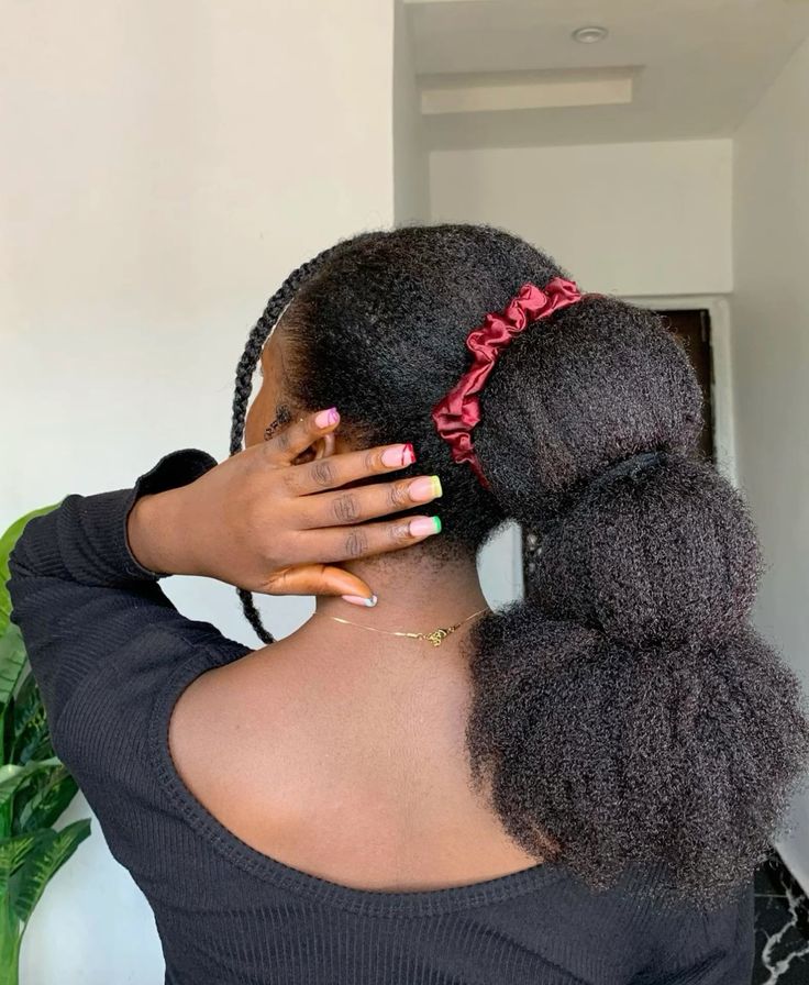 Woman observing healthy natural 4C hair progress after several months.
