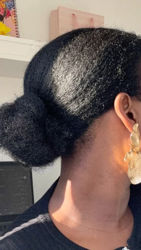 Black woman wearing a loose low bun on healthy natural 4C hair to help 4c hair grow faster naturally