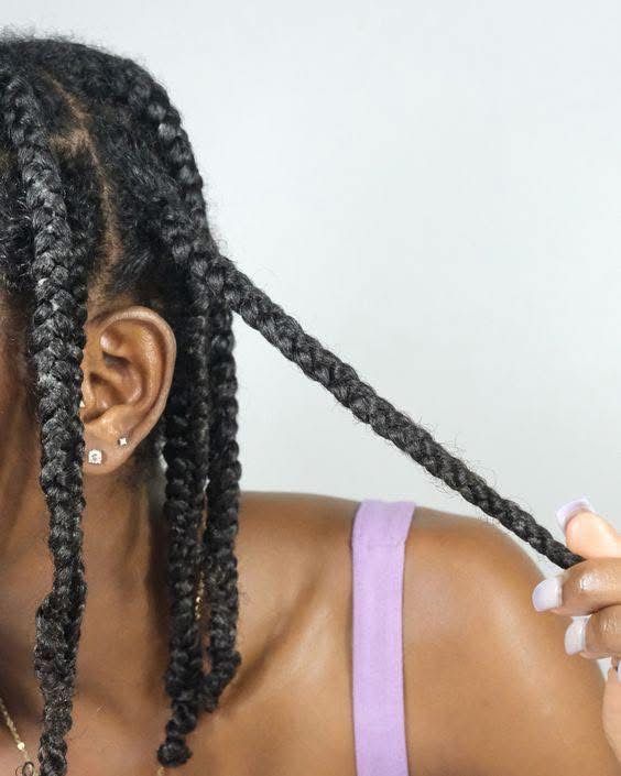 Black woman moisturizing braids on healthy natural 4C hair.