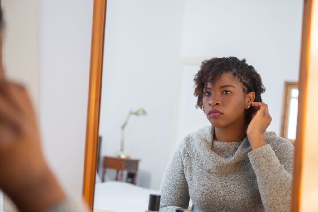 Black woman adjusting her medium twists while caring for her natural hair.