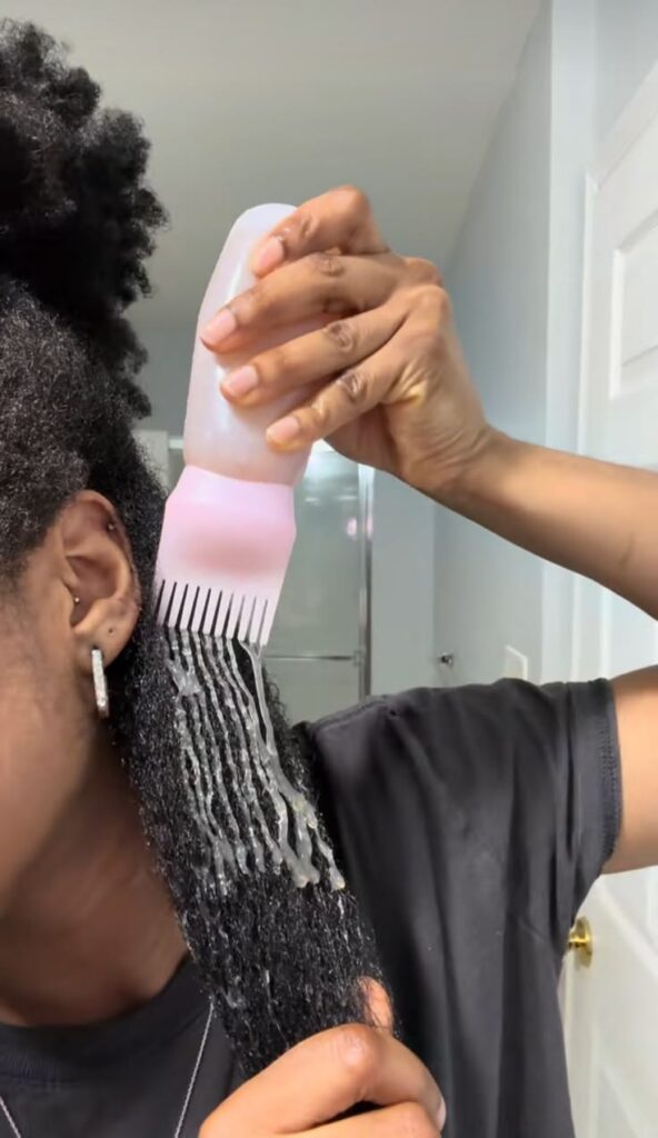Leave-in conditioner being worked through sectioned 4C hair.