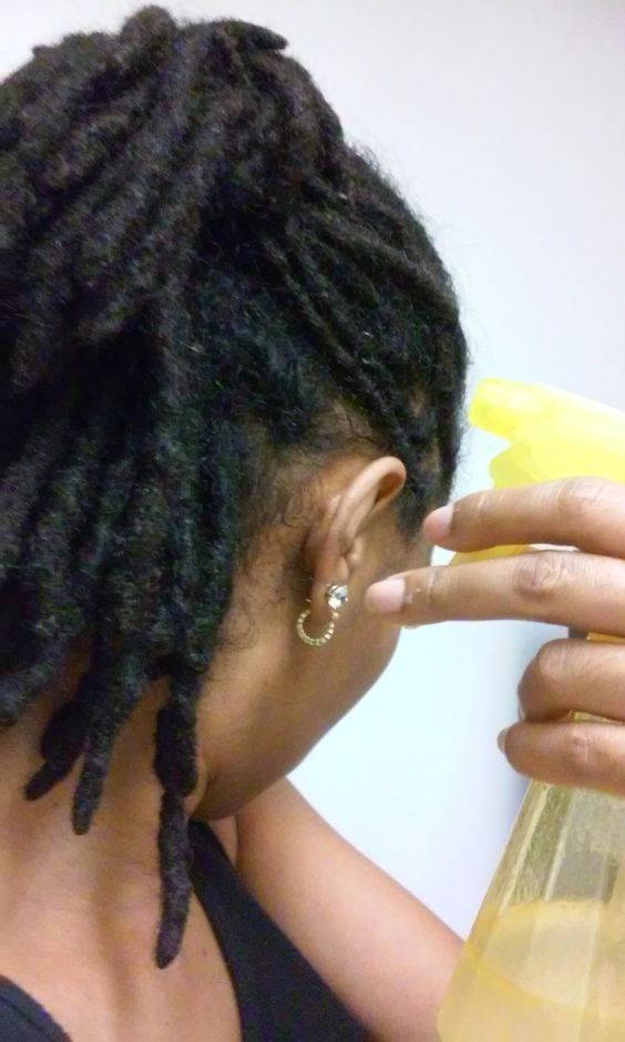 woman spraying her hair with water and oil