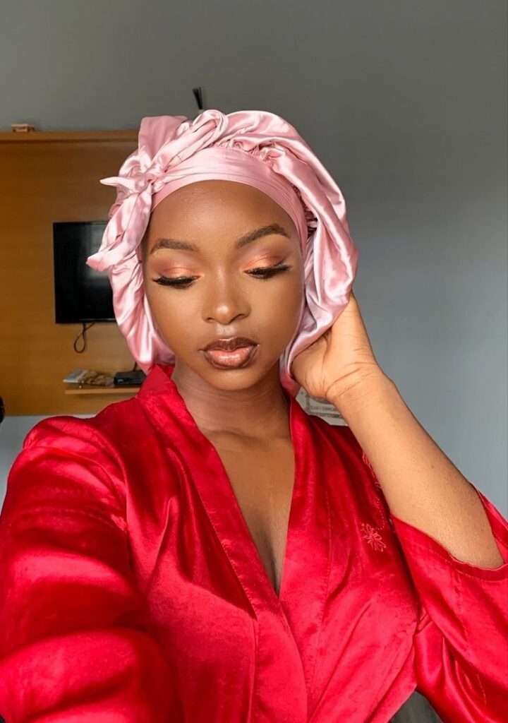 Black woman wearing a satin bonnet to protect her protective styling overnight.
