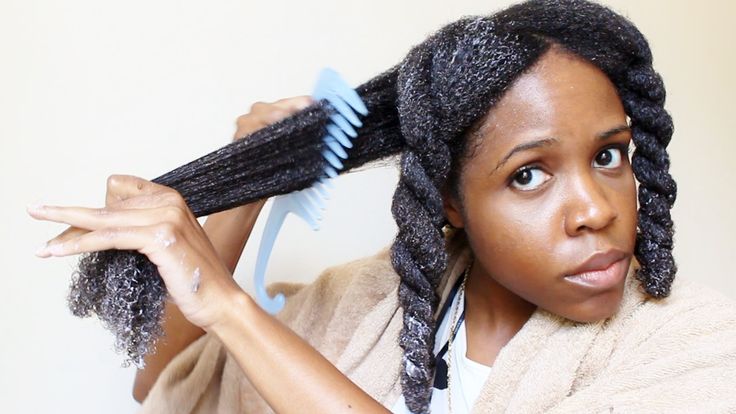 Black woman gently detangling natural 4C hair after removing braids.