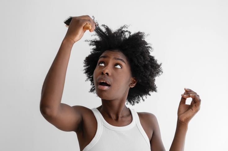 Black woman examining breakage after removing a protective hairstyle.