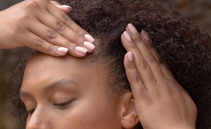 Black woman gently massaging her scalp with her fingertips.