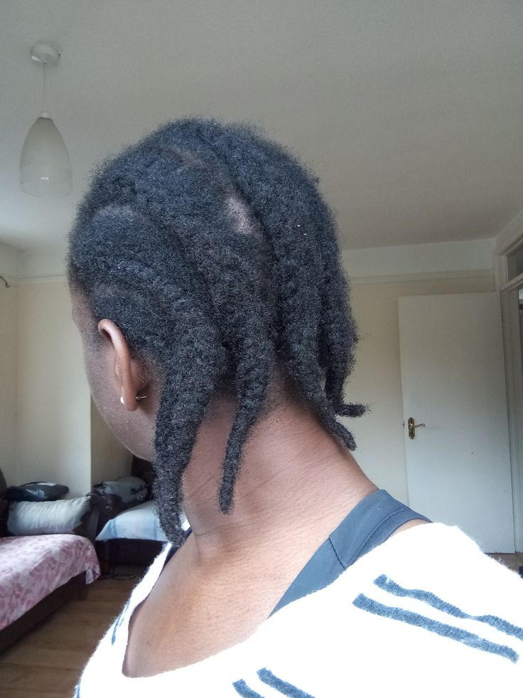 Woman checking frizzy protective hairstyle with excessive new growth.