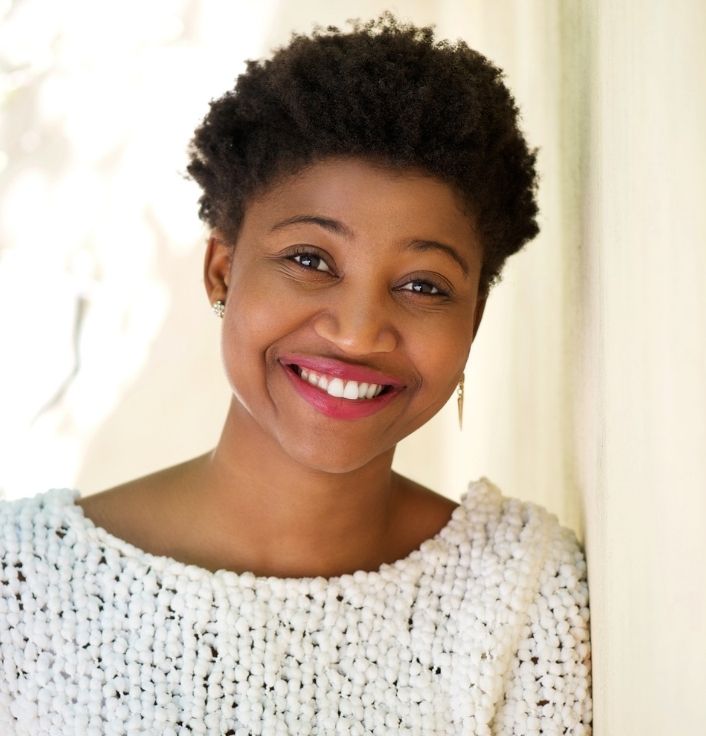 Black woman with healthy natural 4C hair smiling confidently outdoors.