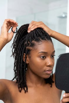 Black woman checking her twists for tension and new growth on natural 4C hair