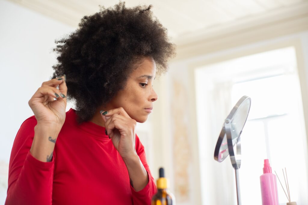 Woman examining her natural hair while building a healthy hair care routine