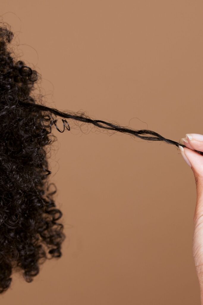 Woman checking the length of her natural hair while wondering why her 4C hair isn't growing.