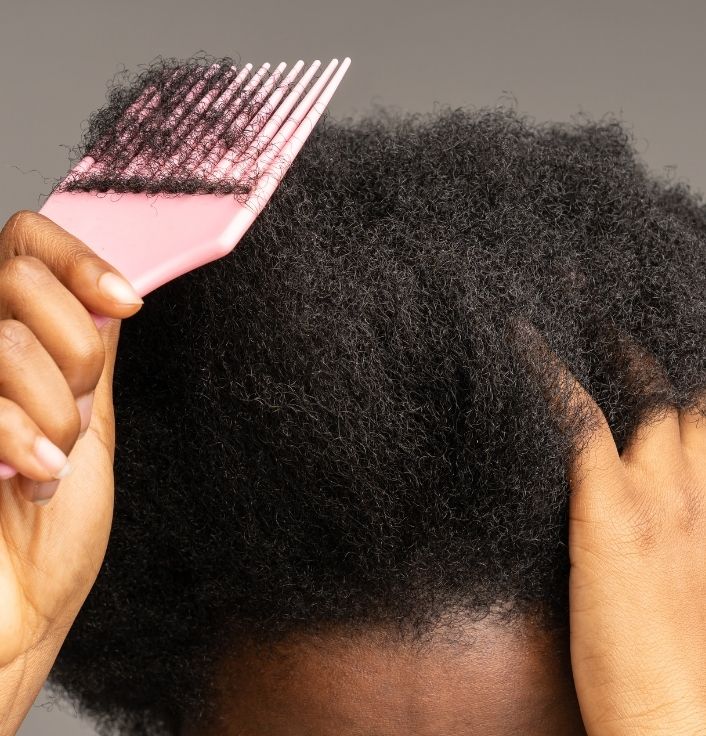 woman fustrated while trying to detangle dry hair