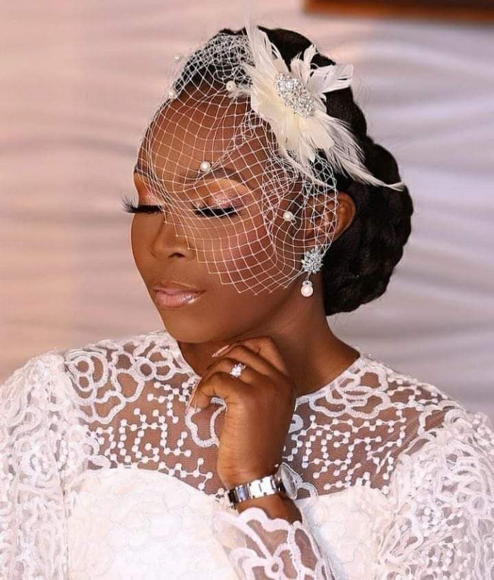 Black bride with natural 4C hair in elegant low bun with stylish bridal fascinator,
