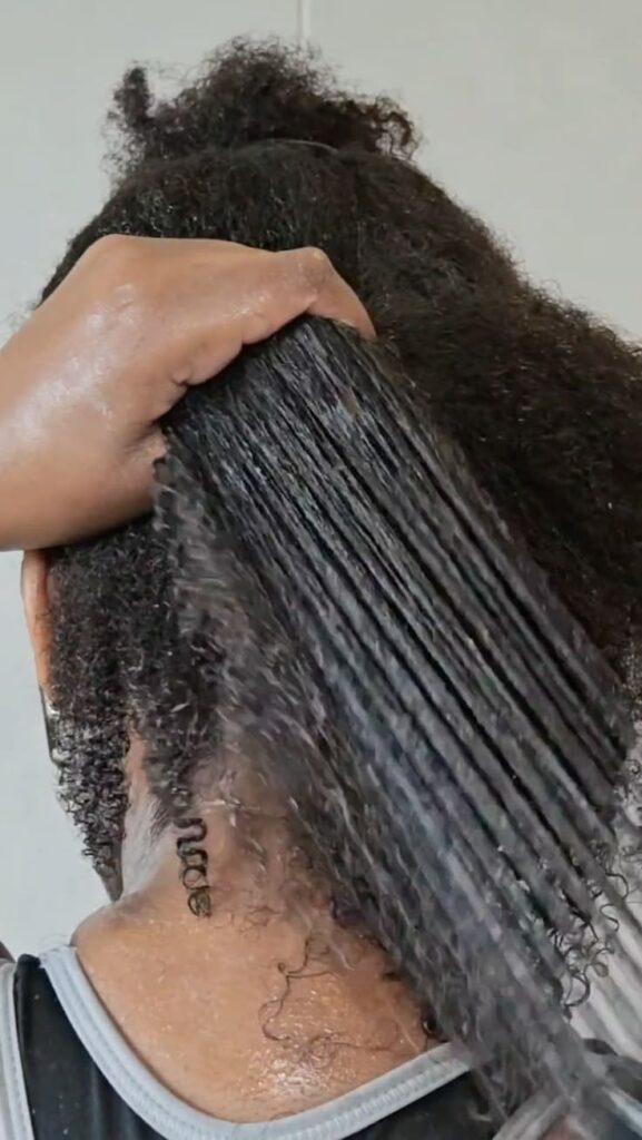 Applying leave-in conditioner to damp high-porosity 4C hair.