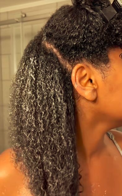 Woman applying conditioner to natural 4C hair