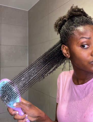 Woman gently detangling sectioned natural 4C hair with conditioner