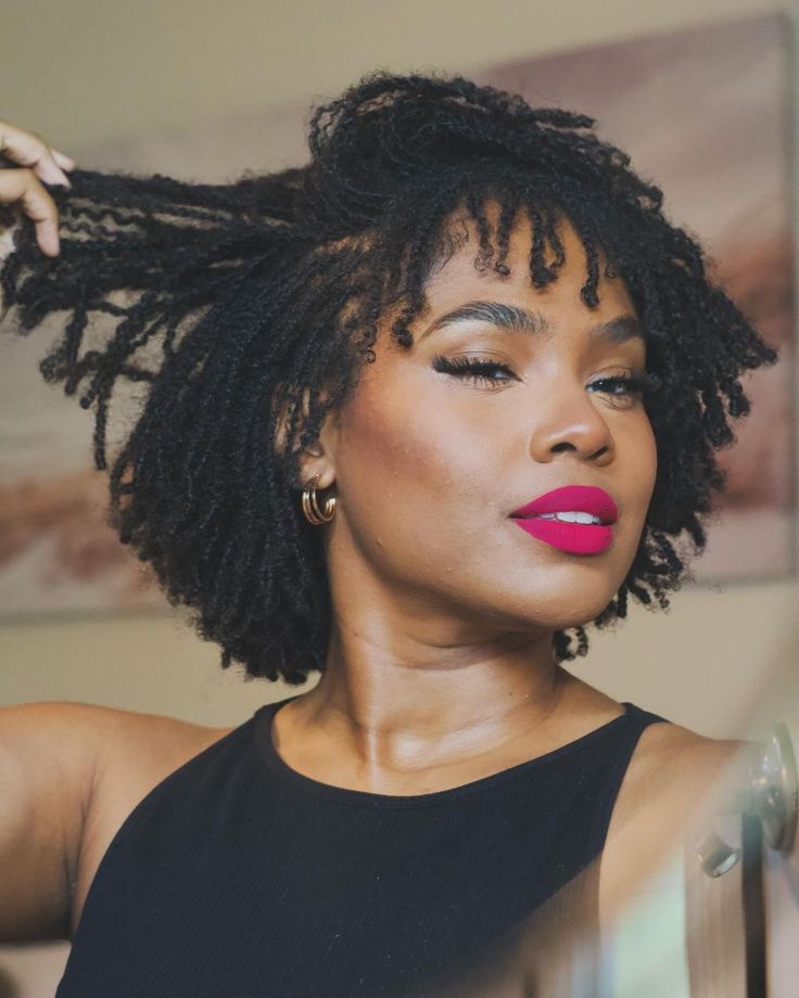 Black woman smiling confidently while embracing her healthy starter loc journey.