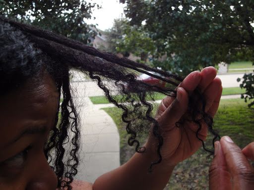 Black woman gently finger detangling her natural hair