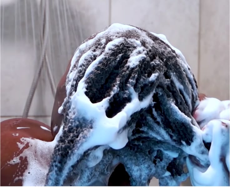 Black woman gently cleansing natural 4C hair in sections