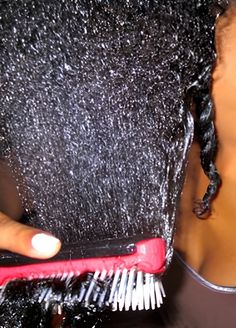 woman gently detangling transitioning hair with visible natural roots and relaxed ends.