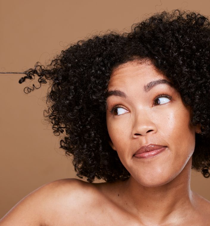 Woman examining healthy 4C hair while learning about hair porosity.