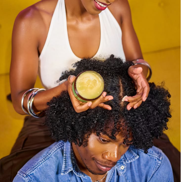 Healthy-looking natural hair being gently styled with a small amount of hair butter.