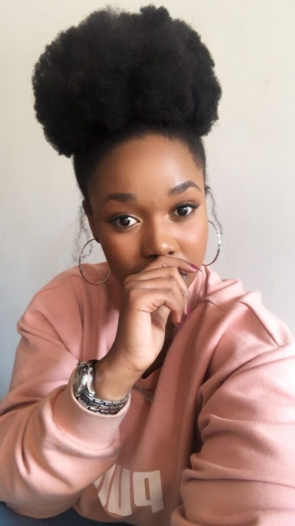 Black woman wearing a cute full high afro puff on natural 4C hair
