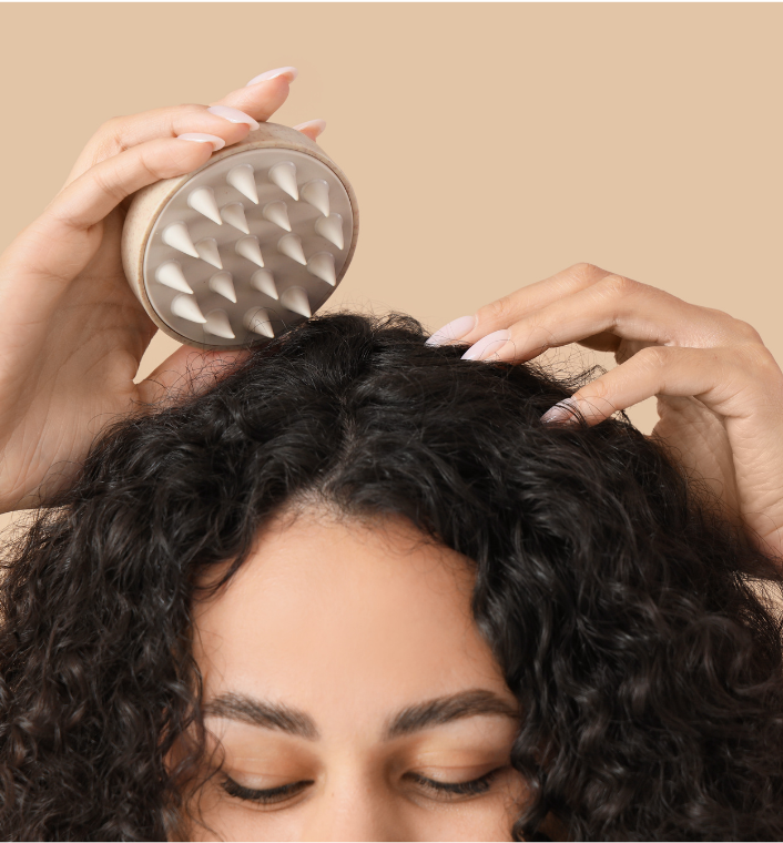 A woman with natural hair gently touching or massaging her scalp.