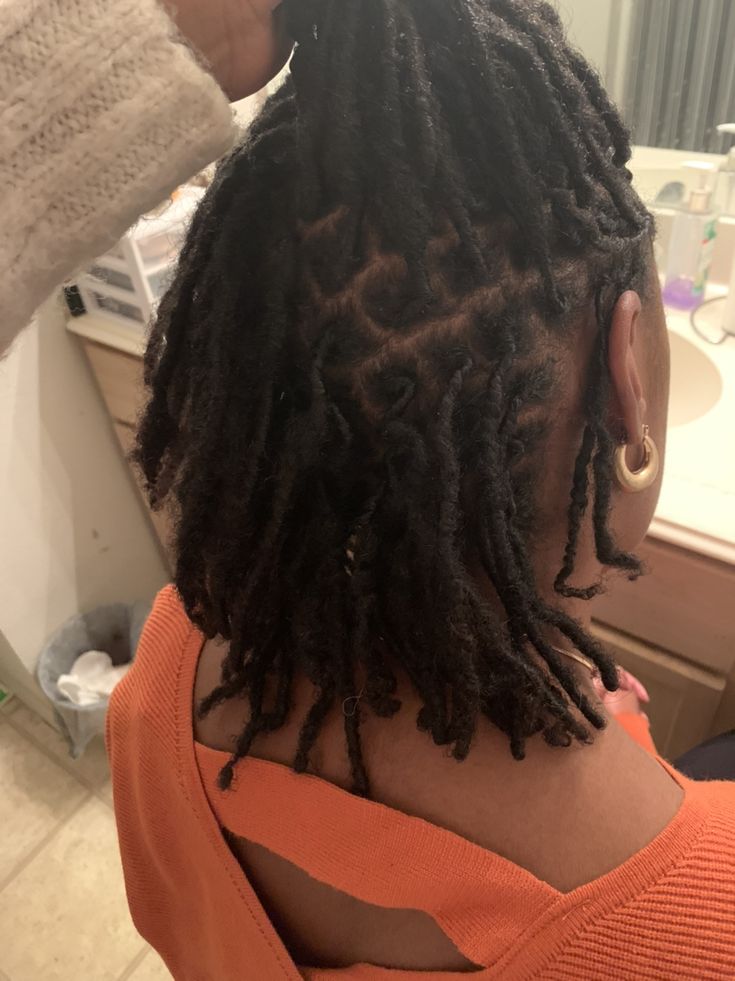 Black woman having her starter locs professionally retwisted.