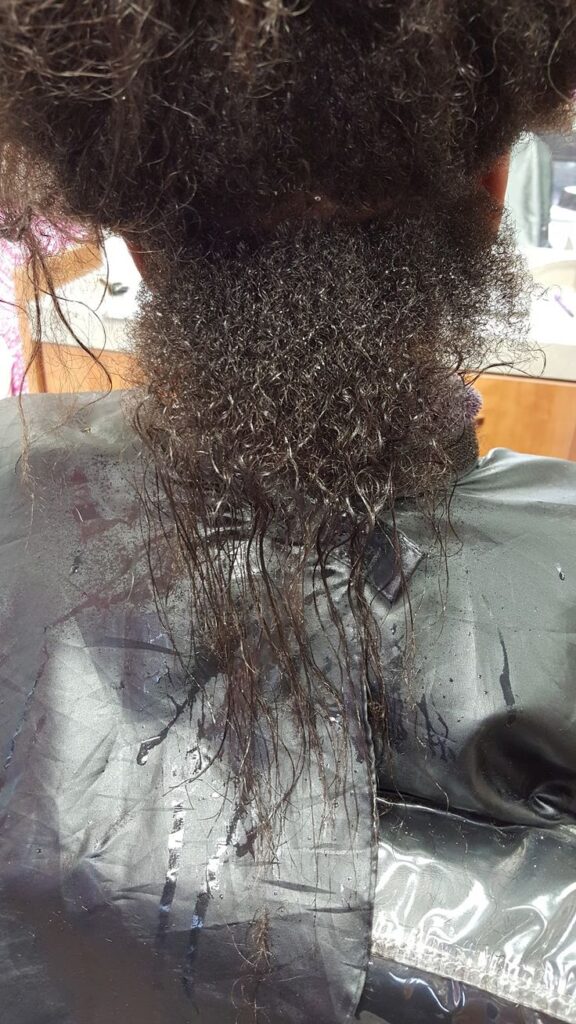 Black woman transitioning from relaxed hair to natural 4C hair with several inches of new growth.