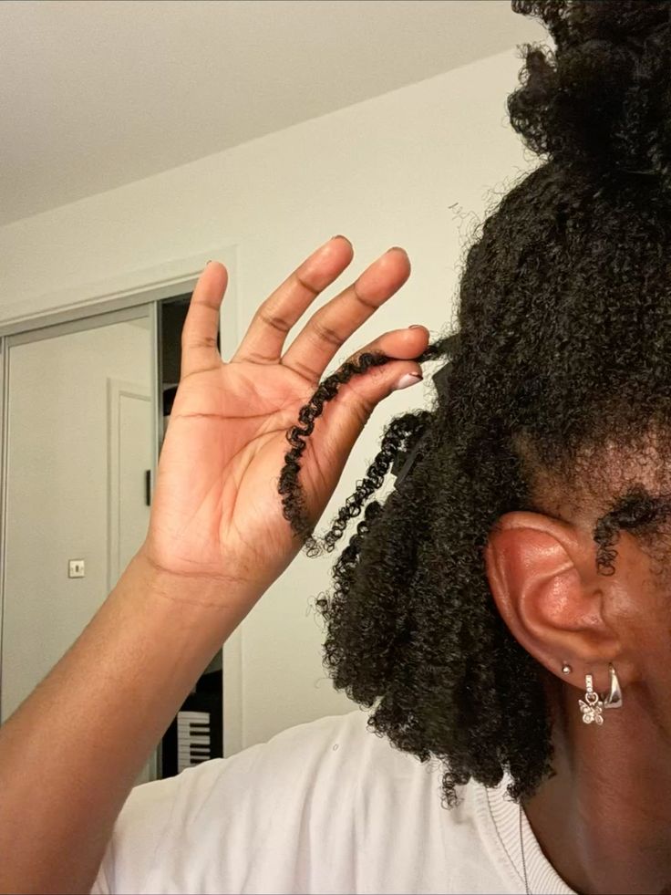 Woman examining her natural low-porosity 4C hair.