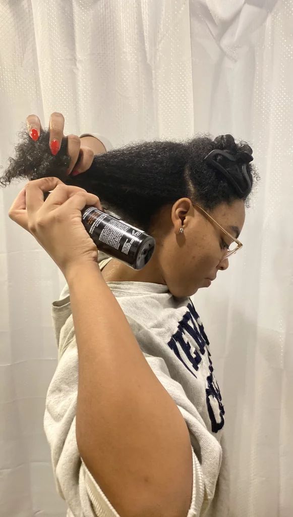 woman applying heat protectant before styling natural 4C hair