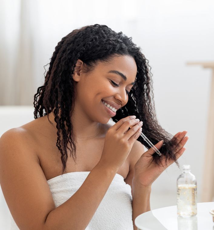 Natural oil being applied to seal moisture in high-porosity 4C hair.