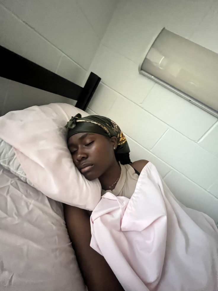 Woman sleeping with a satin scarf and pillowcase to protect natural 4C hair.