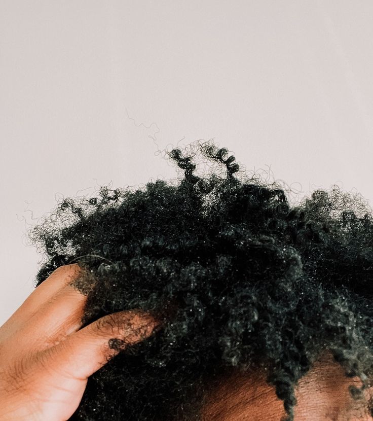 A woman gently checking her scalp with her fingertips.