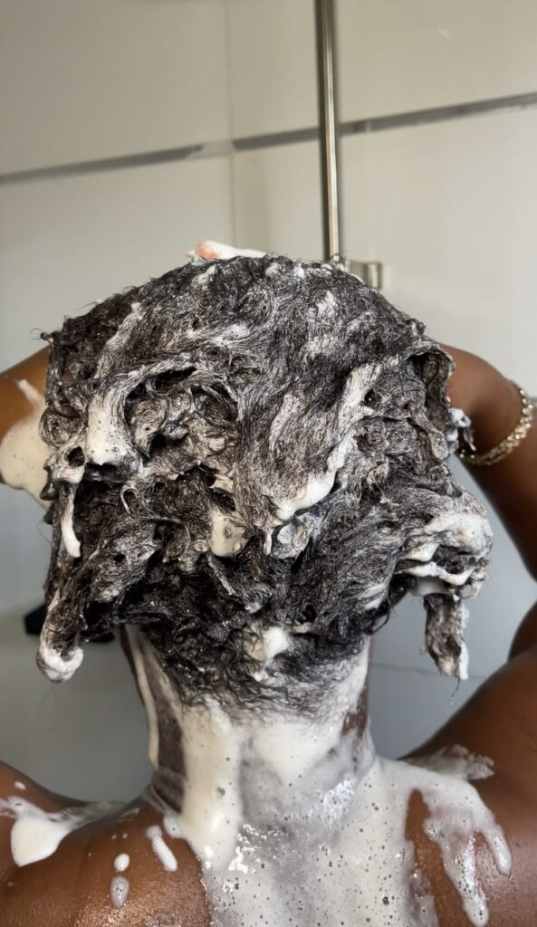 Black woman washing natural 4C hair in a shower