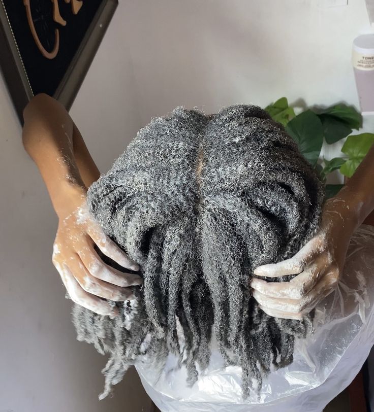 A natural-haired woman applying a hair mask during wash day.